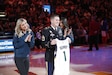 U.S. Army Soldier stands on an NBA court holding a personalized jersey. Two NBA cheerleaders stand on either side of him