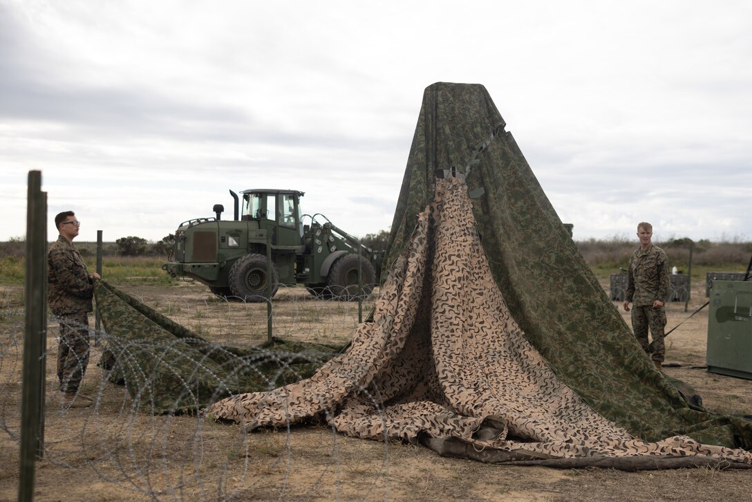 U.S. Marines with Combat Service Support Company, I Marine Expeditionary Force Support Battalion, I MEF Information Group set up camouflage netting in support of Exercise Steel Knight on Marine Corps Base Camp Pendleton, California, Nov. 29, 2023. Steel Knight 23.2 is a three-phase exercise designed to train I Marine Expeditionary Force in the planning, deployment and command and control of a joint force against a peer or near-peer adversary combat force and enhance existing live-fire and maneuver capabilities of the Marine Air-Ground Task Force. (U.S. Marine Corps photo by Lance Cpl. Tyler D. Wilson)