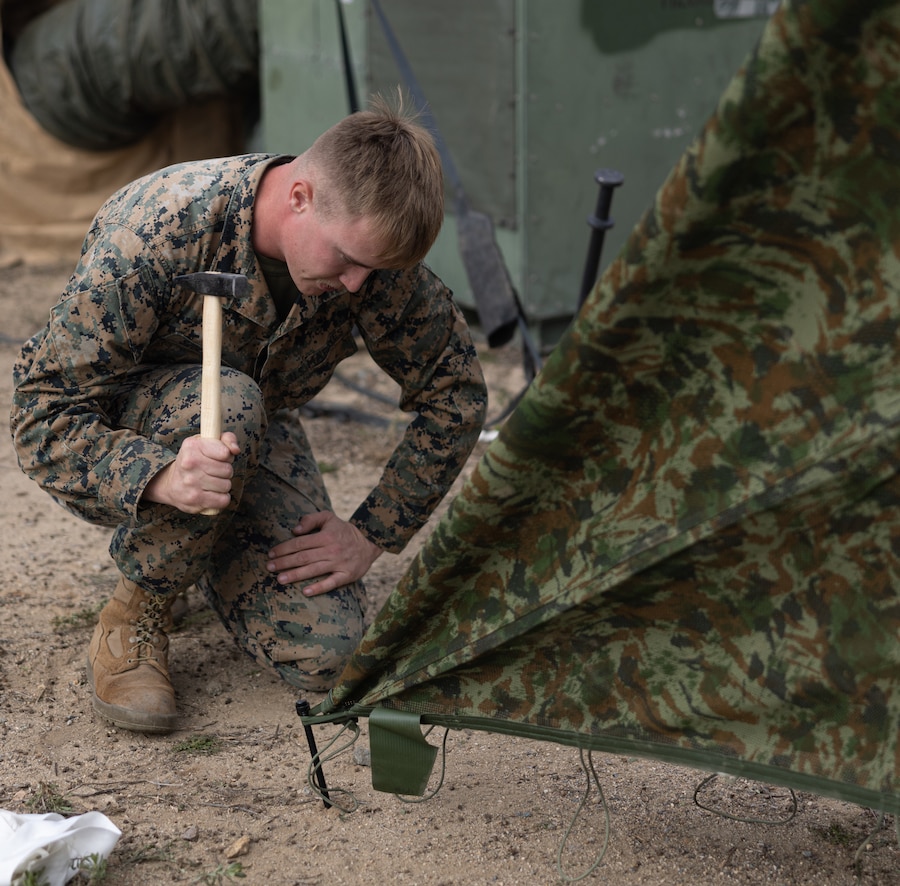 A U.S. Marine with Combat Service Support Company, I Marine Expeditionary Force Support Battalion, I MEF Information Group set up camouflage netting in support of Exercise Steel Knight on Marine Corps Base Camp Pendleton, California, Nov. 29, 2023. Steel Knight 23.2 is a three-phase exercise designed to train I Marine Expeditionary Force in the planning, deployment and command and control of a joint force against a peer or near-peer adversary combat force and enhance existing live-fire and maneuver capabilities of the Marine Air-Ground Task Force. (U.S. Marine Corps photo by Lance Cpl. Tyler D. Wilson)