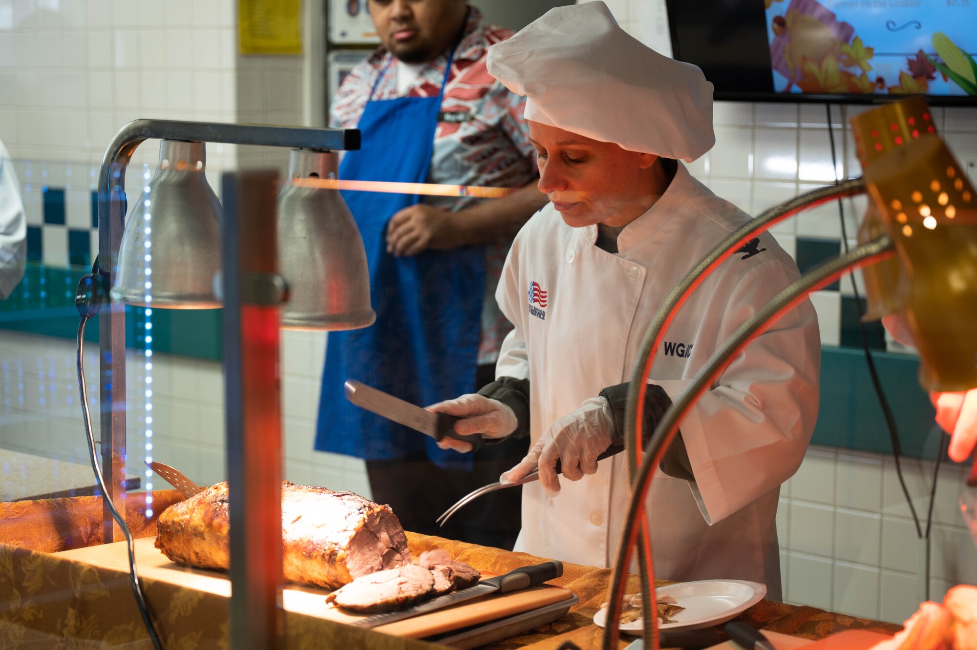 Col. Michele Lo Bianco, 15th Wing commander, carves roast beef for an Airman during a lunch at Joint Base Pearl Harbor-Hickam, November 23, 2023. Leaders from the 15th Wing showed their appreciation to Airmen and their families by serving them lunch on Thanksgiving. (U.S. Air Force photo by 2nd Lieutenant Margaret Blice)