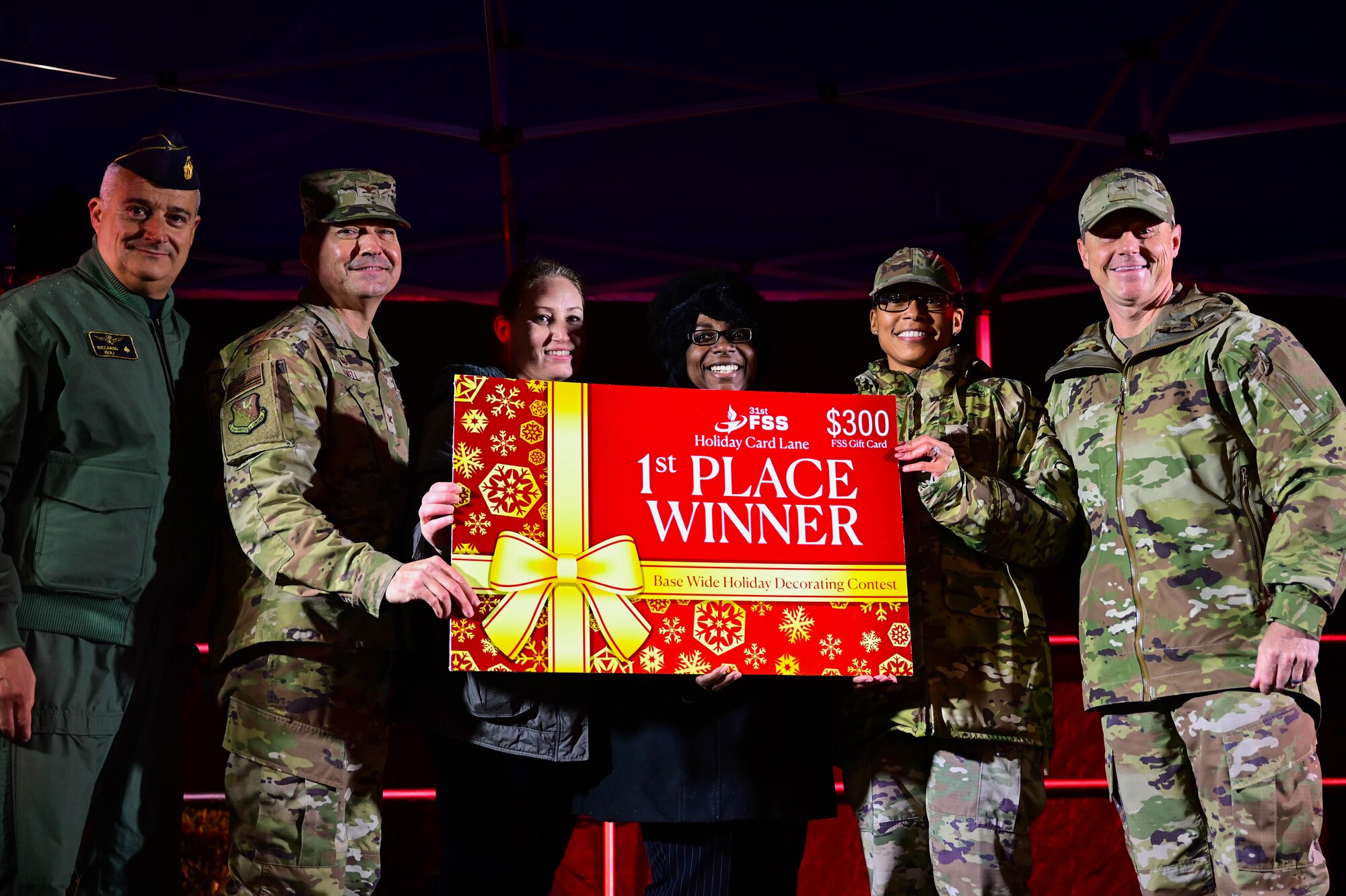 U.S. Air Force Brig. Gen. Tad Clark, 31st Fighter Wing commander, far right, and Italian Air Force Lt. Col. Riccardo Isoli, operations chief, far left, present first place for the holiday card decoration contest prize to representatives from the 31st Medical Group during Wyvern Wonderland.