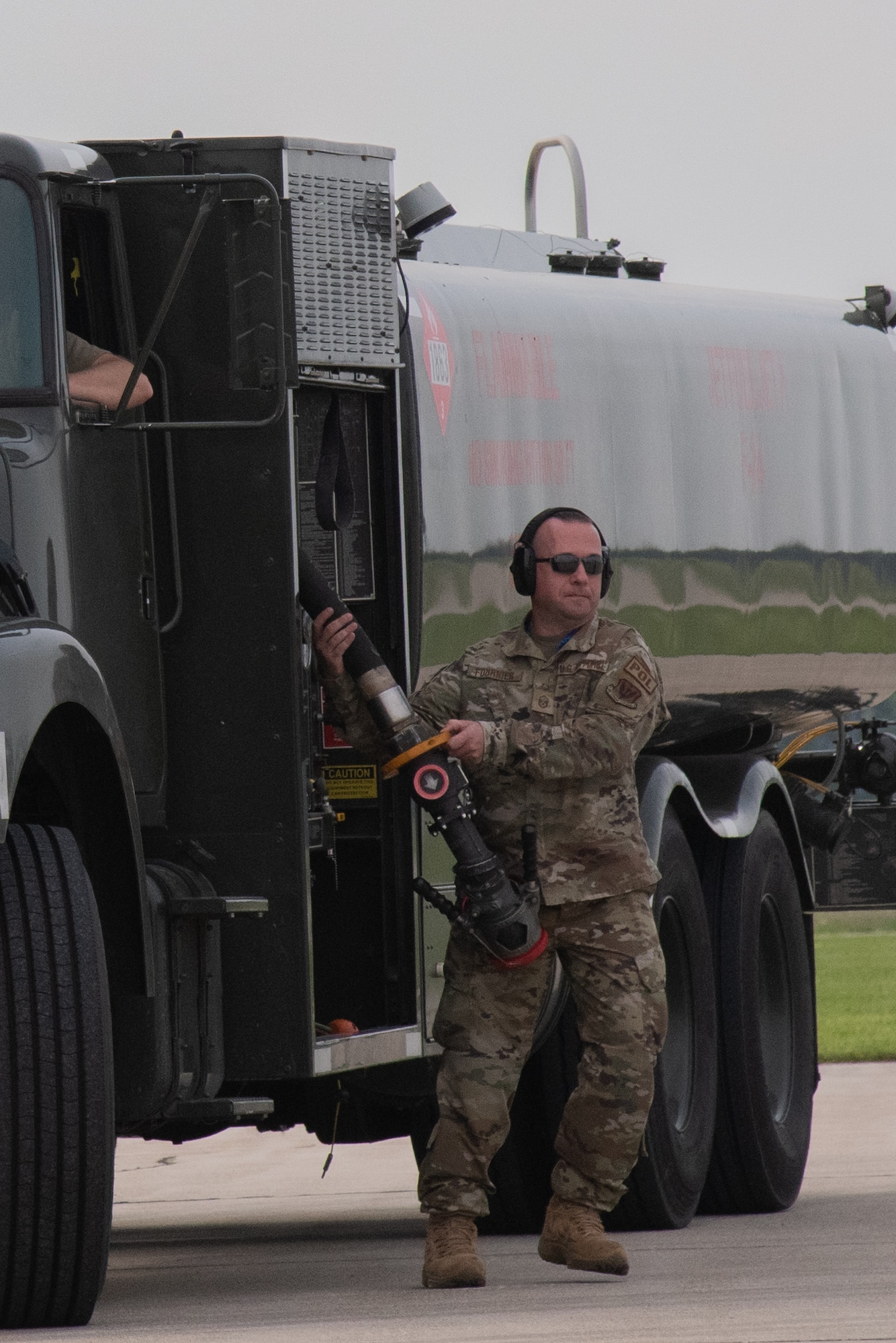 Airmen pulls fuel hose from fuel truck.