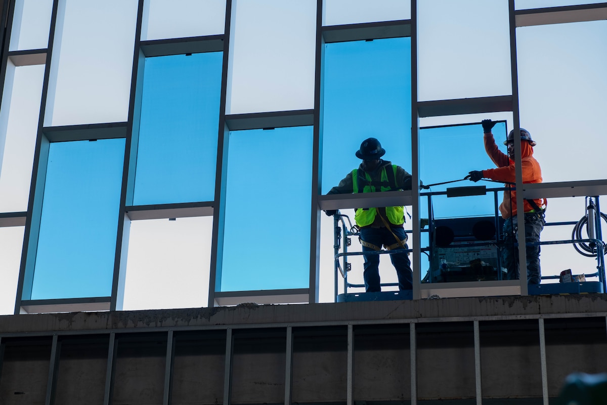 Construction workers install mirrored glass windows into the lobby of the new lodging facility.