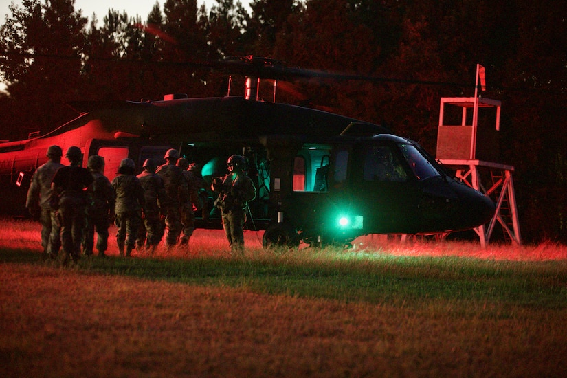 U.S. Army Reserve Soldiers prepare to board a Blackhawk helicopter at night.
