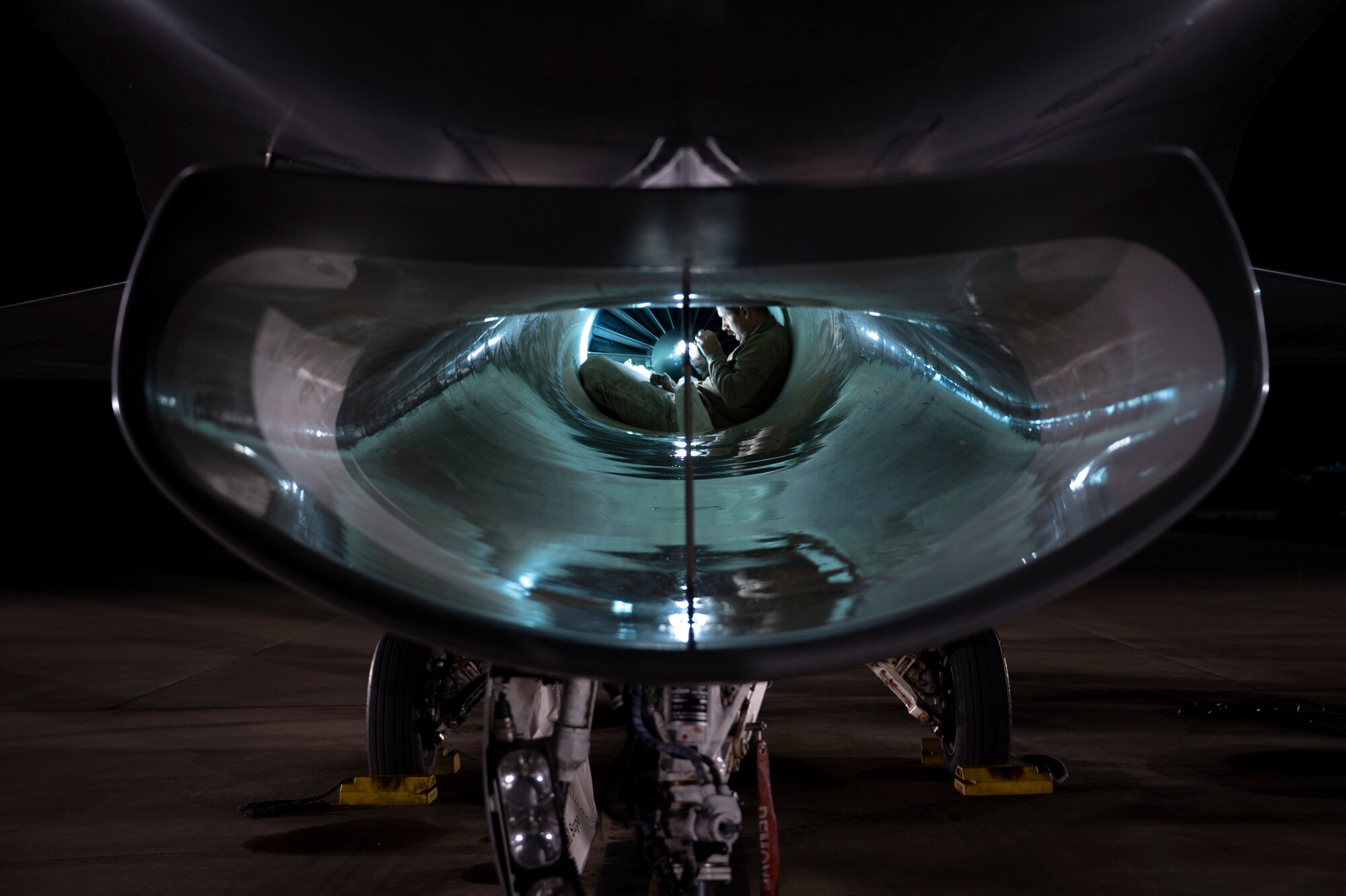 U.S. Air Force Staff Sgt. Nathan Nybakke, 311th Maintenance Squadron Propulsion non-commissioned officer in charge, performs intake inspection of F-16 Viper at Holloman Air Force Base, New Mexico, Nov. 16. 2023. High-power engine run maintenance involves verification of serviceability of the aircraft and engine prior to and after flight or maintenance completion. (U.S. Air Force photo by U.S. Air Force Airman 1st Class Michelle Ferrari)