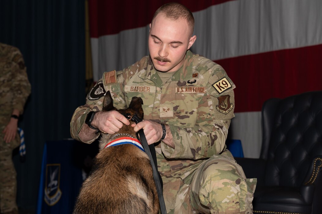 U.S. Air Force Senior Airman Joshua Barber, 354th Security Forces Squadron military working dog handler, places a retirement collar on Military Working Dog Oogre on Eielson Air Force Base, Alaska, Nov. 17, 2023.