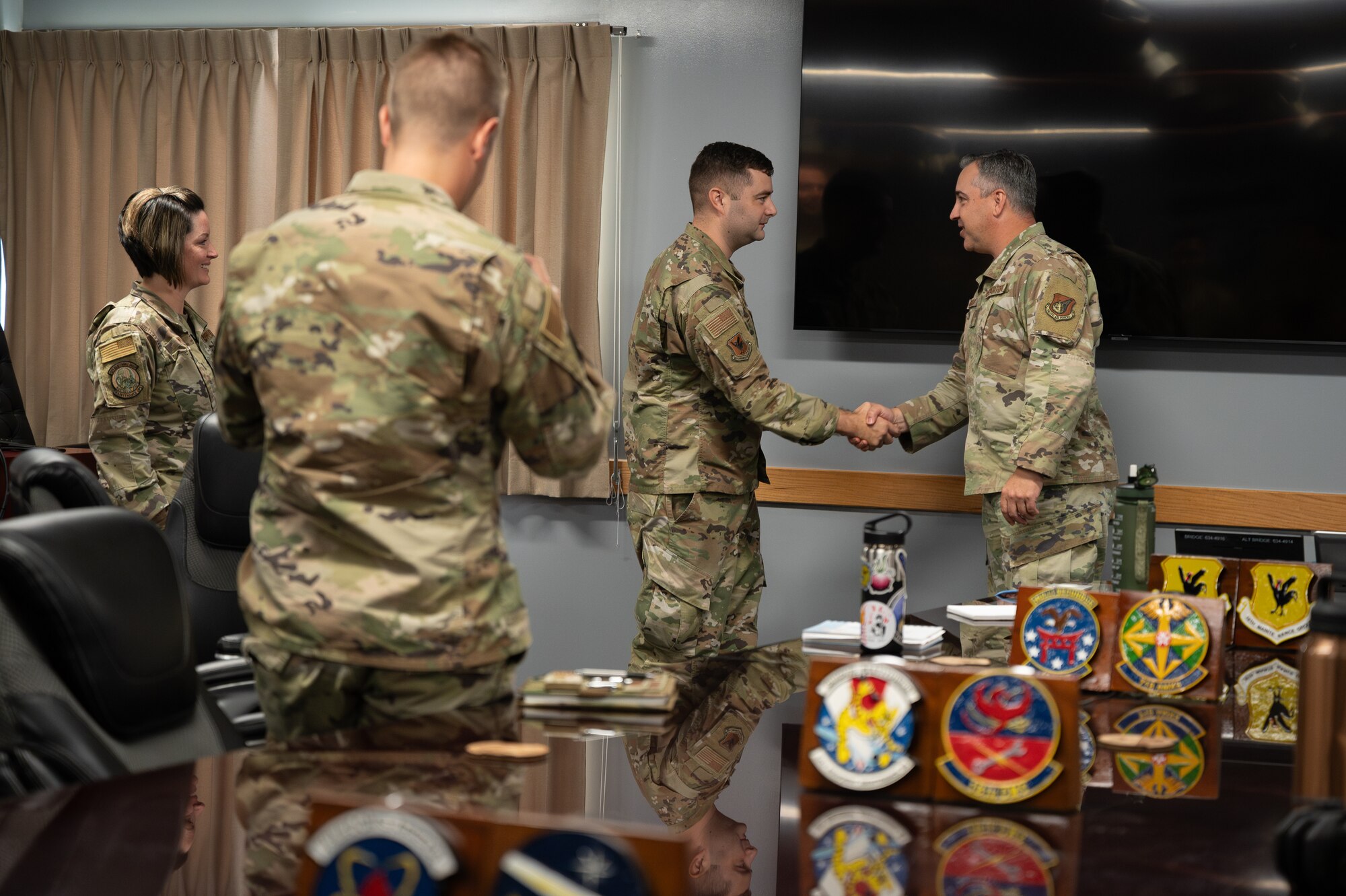 Two Airman shake hands while two others watch.