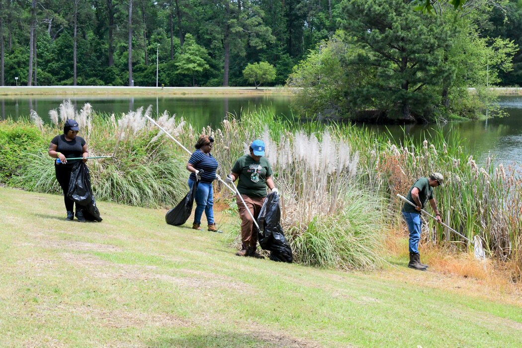 A group of people picking up trash by a lake