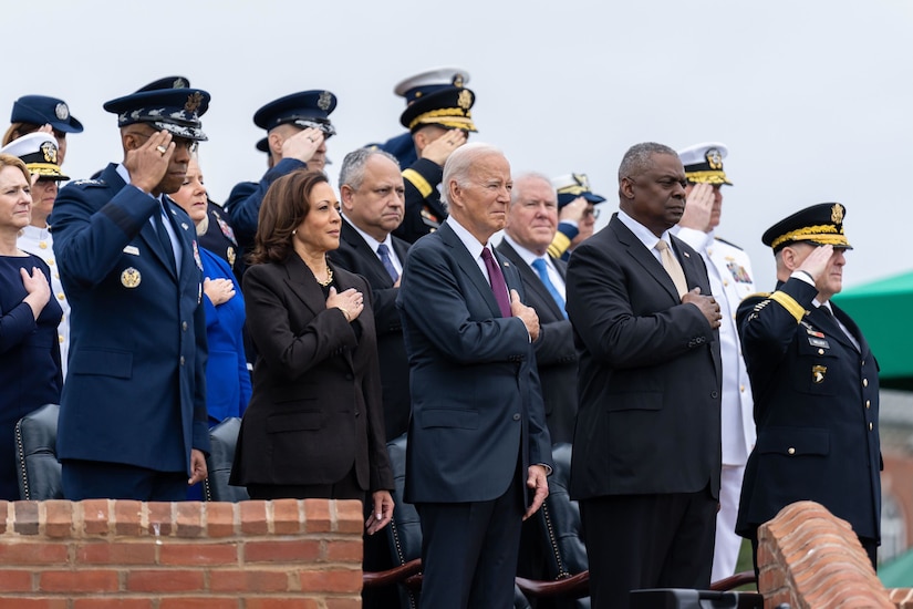 Leaders render honors while standing in a row at an outdoor ceremony.