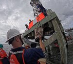 Chief Petty Officer Dana Wise, Coast Guard Aids to Navigation Team St. Petersburg, passes threaded bolts to the team replacing the boards on the Alafia River Rear Range Light, on the Alafia River, Wednesday, Sept. 27, 2023. The boards were damaged during Hurricane Idalia, creating an aid-to-navigation discrepancy and hazard to navigation. (U.S. Coast Guard photo by Petty Officer 1st Class Nicole J. Groll)