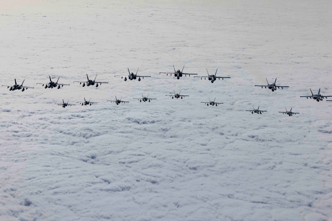 Aircraft fly in formation over clouds.