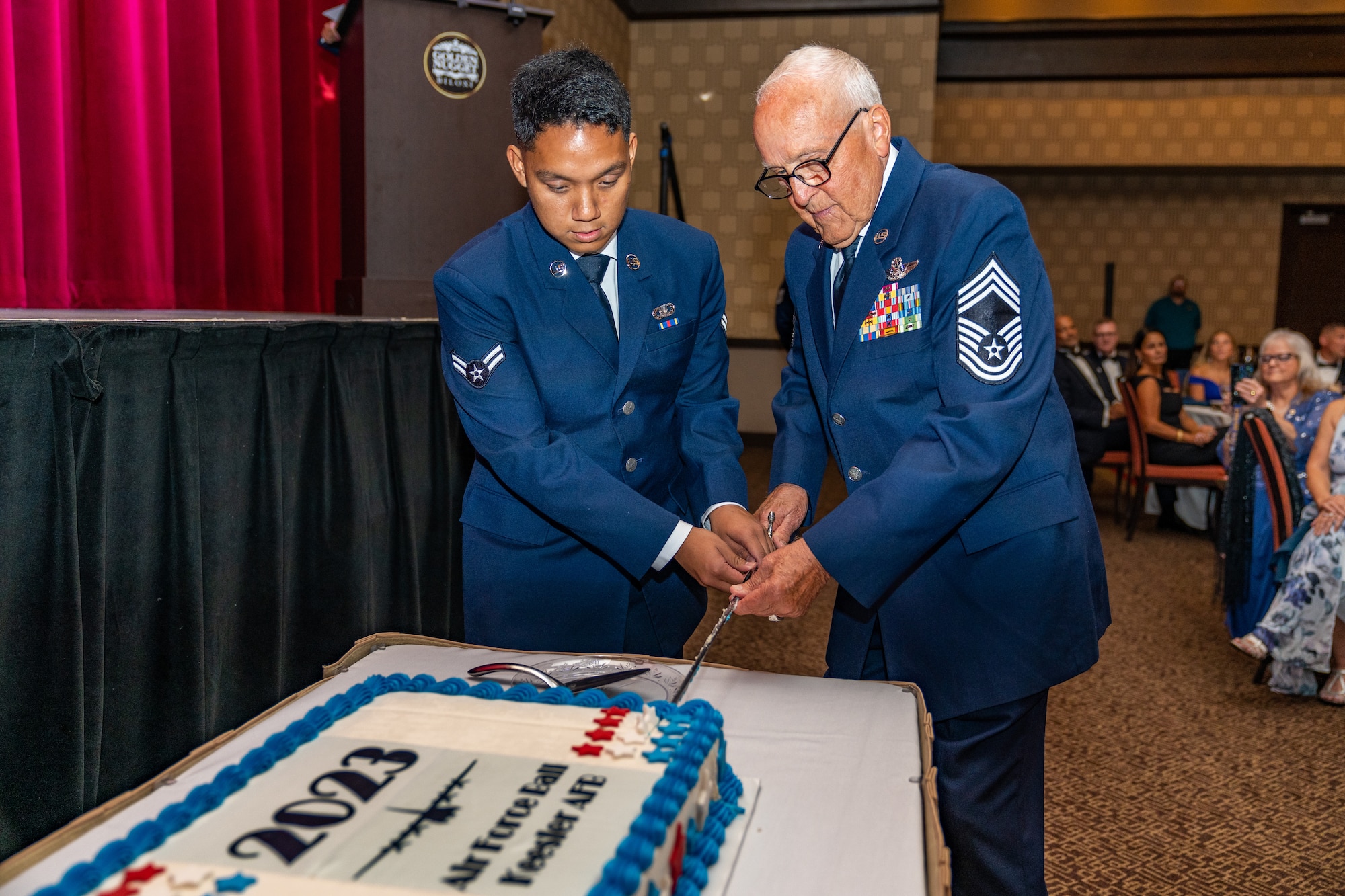 Retired U.S. Air Force Chief Master Sgt. (Retired) Edward Farley, and Airman 1st Class Jason Siacunco, 81st Training Wing, religious affairs, cut the birthday cake during the 2023 Air Force Ball at the Golden Nugget Casino, Mississippi, Sept. 23, 2023.