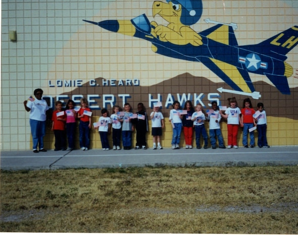 Class picture while holding flags at the school mural, class and date unknown.