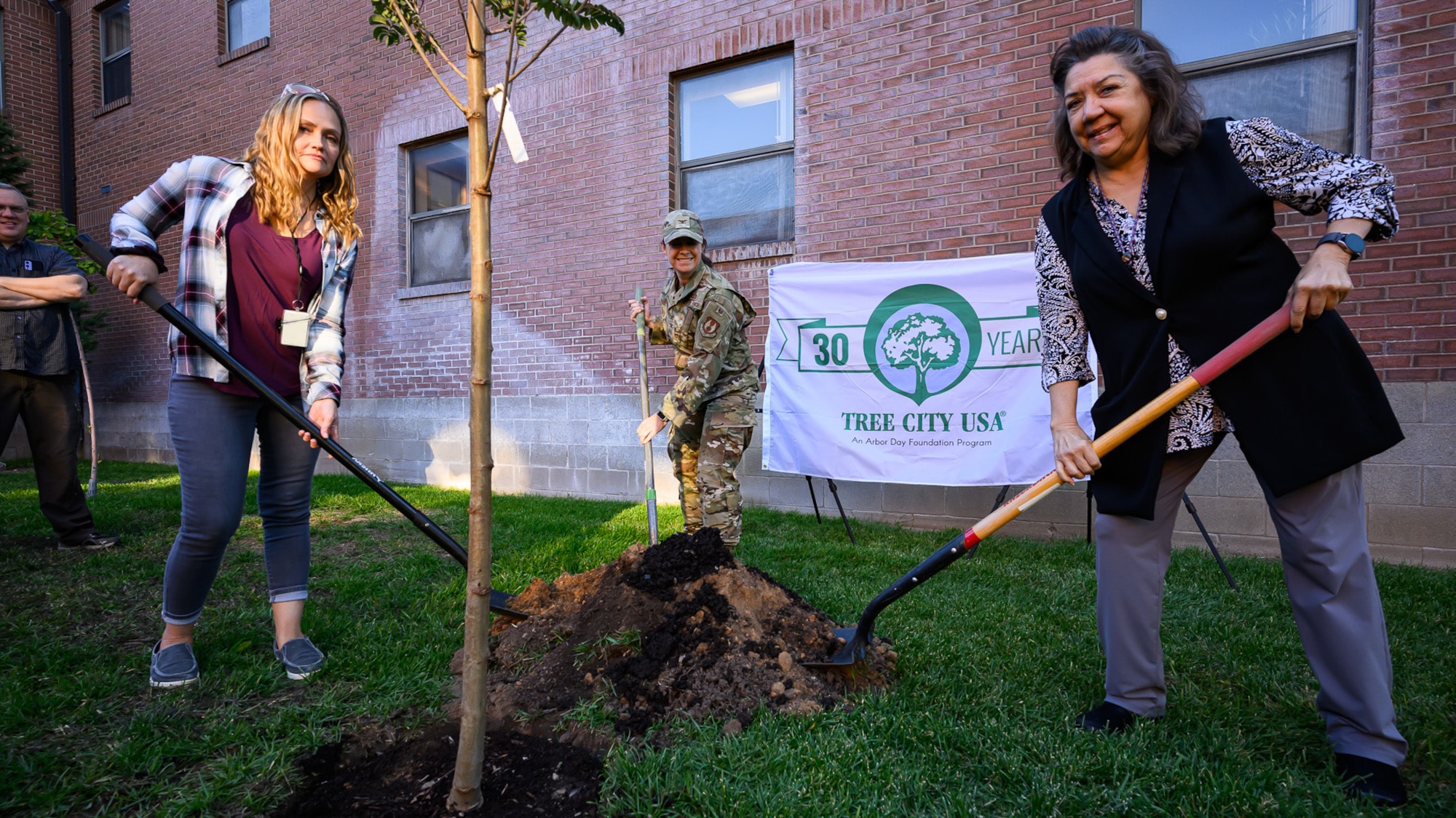 Three ladies ceremoniously plant a tree