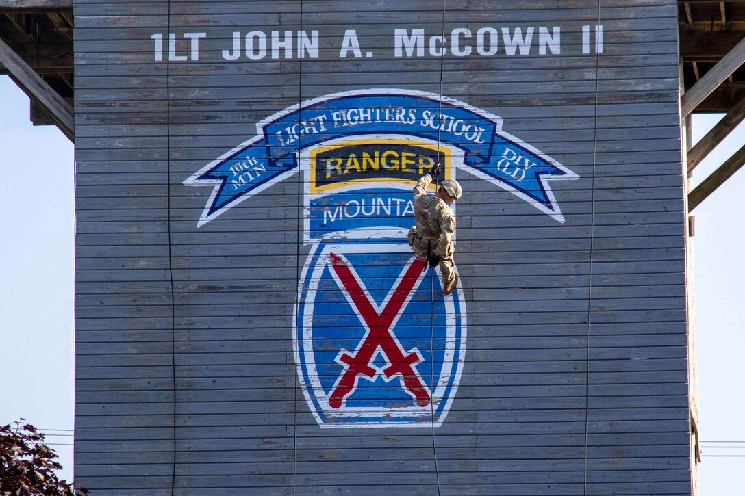 A soldier rappels down a rappel tower.