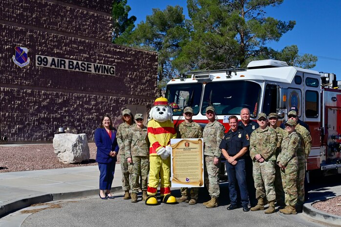 U.S. Air Force Col. Joshua DeMotts, 99th Air Base Wing commander, stands in front of a fire truck for a group photo with members of the 99th Civil Engineering Squadron and the 2023 Fire Prevention Week Proclamation.