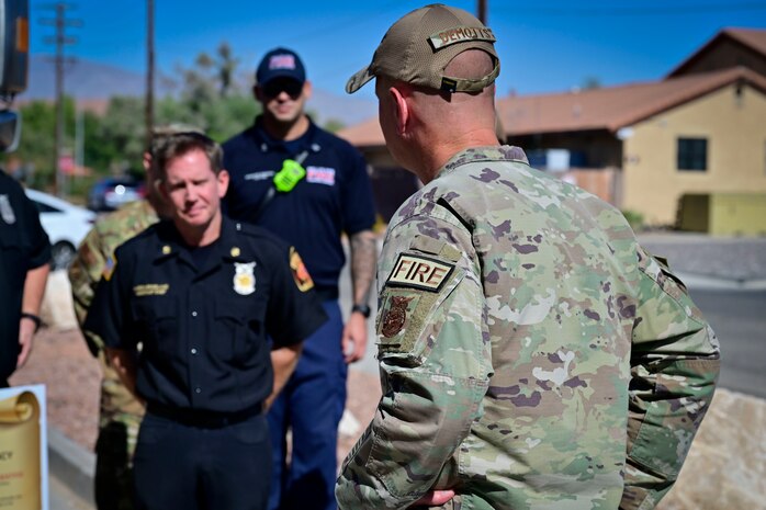 U.S. Air Force Col. Joshua DeMotts, 99th Air Base Wing commander, dons a Fire Duty Identifier Patch and Fire Protection badge as he speaks to members of 99th Civil Engineering Squadron.