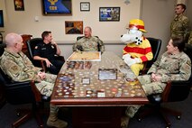 U.S. Air Force Col. Joshua DeMotts, 99th Air Base Wing commander, center, sits around a conference room table with members of the 99th Civil Engineering Squadron before signing the 2023 Fire Prevention Week Proclamation.