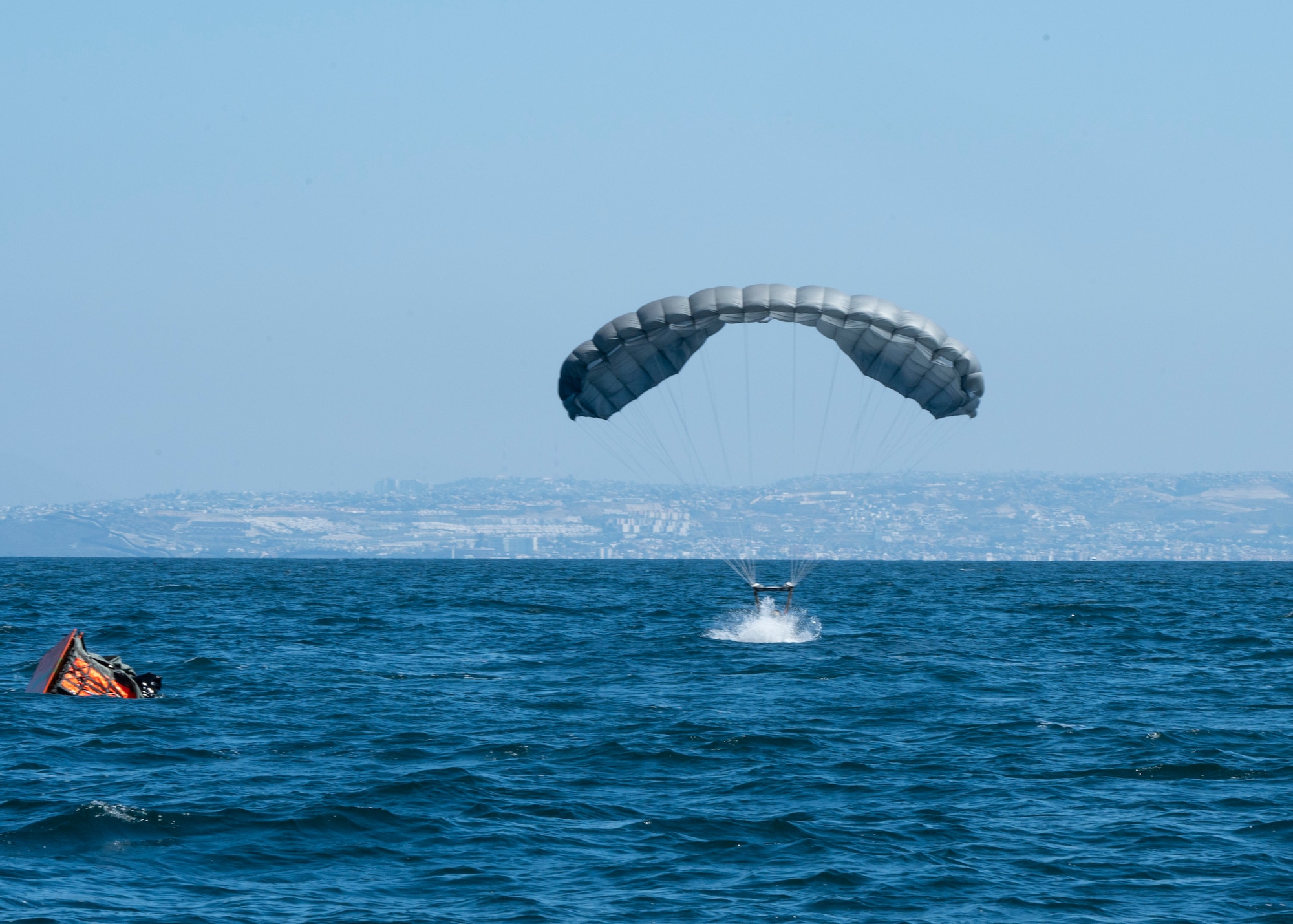 A U.S. Airman, training with the 68th Rescue Squadron, parachutes into a specifically marked drop zone in the ocean near San Diego, Calif., Sept. 6, 2023. The Airman was the first of his team to land at the drop zone and was required to swim to and begin setting up a Rigged Alternate Method Boat. (U.S. Air Force photo by Airman 1st Class William Finn V)