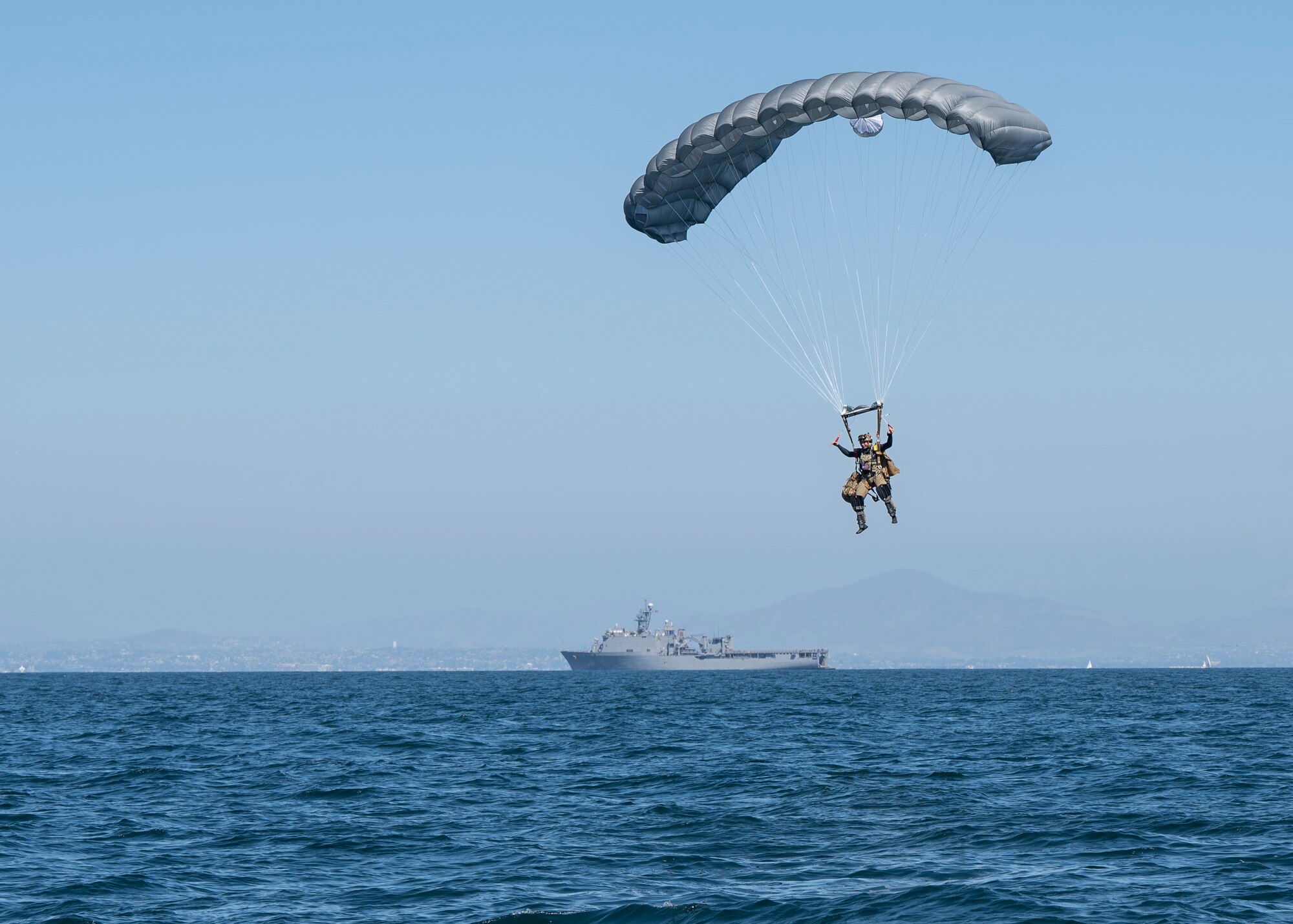 A U.S. Airman, training with the 68th Rescue Squadron, parachutes above the ocean near San Diego, Calif., Sept. 6, 2023. The Airman was required to jump into a specific drop zone, locate a pre-dropped raft and prepare it for rescuing simulated casualties. (U.S. Air Force photo by Airman 1st  Class William Finn V)