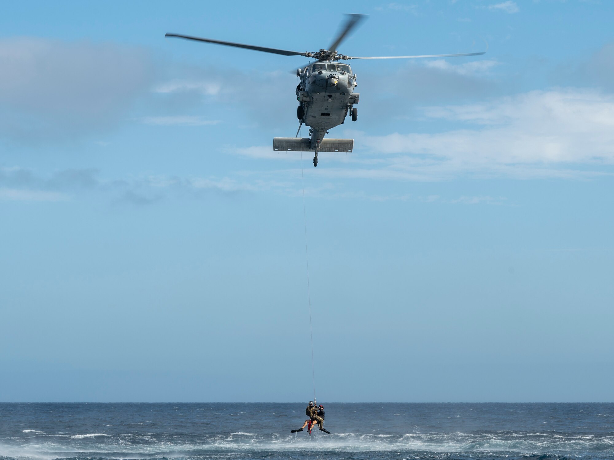 U.S. Airmen, training with the 68th Rescue Squadron, hang below an aircraft off the coast of Calif., Sept. 12, 2023. The Airmen had previously conducted training in rescuing simulated casualties from a boat and exfiltrating them into the water and then onto the aircraft. (U.S. Air Force photo by Airman 1st Class William Finn V)