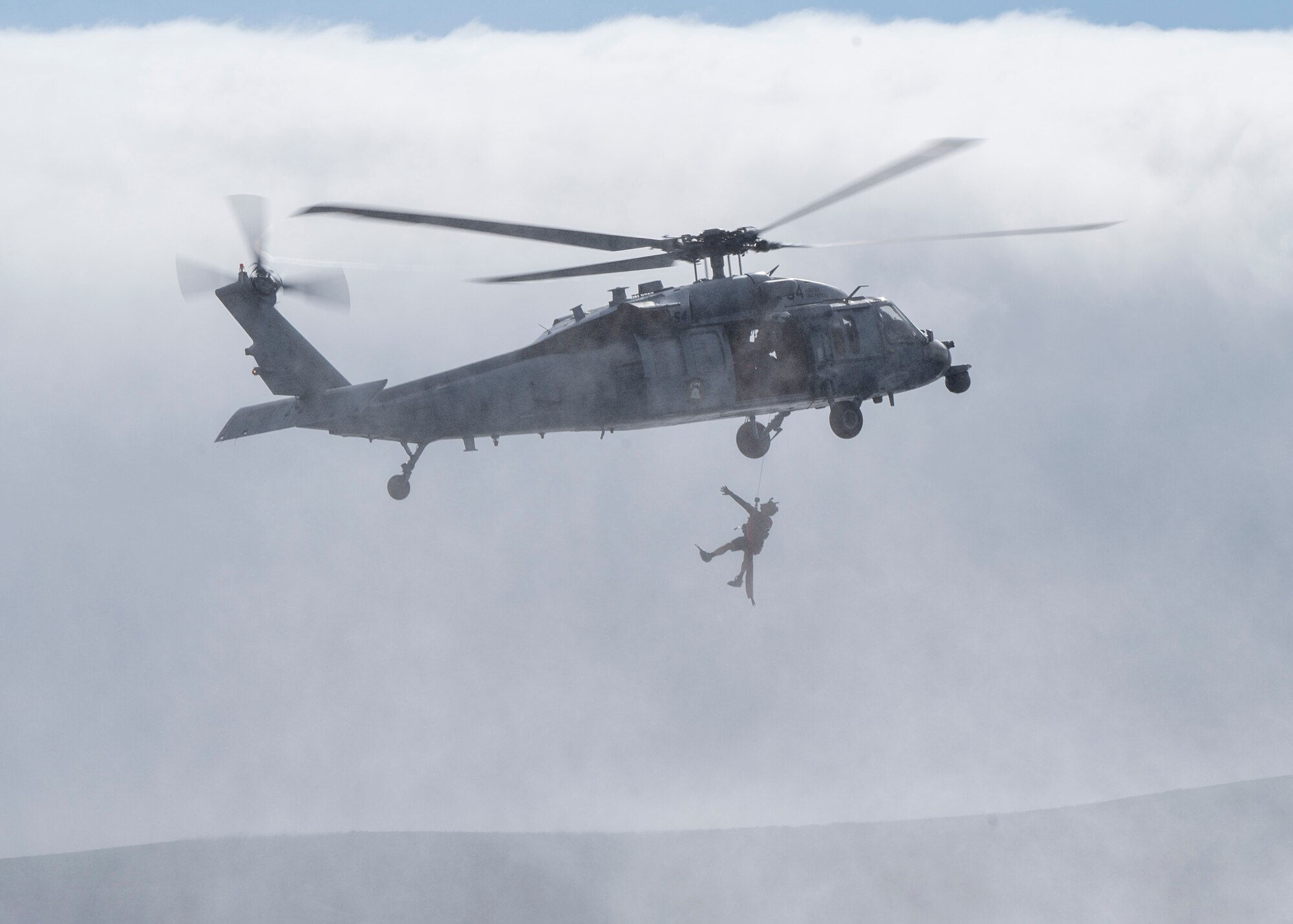 A U.S. Airman, training with the 68th Rescue Squadron, ascends into an aircraft off the coast of Calif., Sept. 12, 2023. The Airman had previously assisted a simulated casualty into the aircraft before boarding for exfiltration. (U.S. Air Force photo by Airman 1st Class William Finn V)