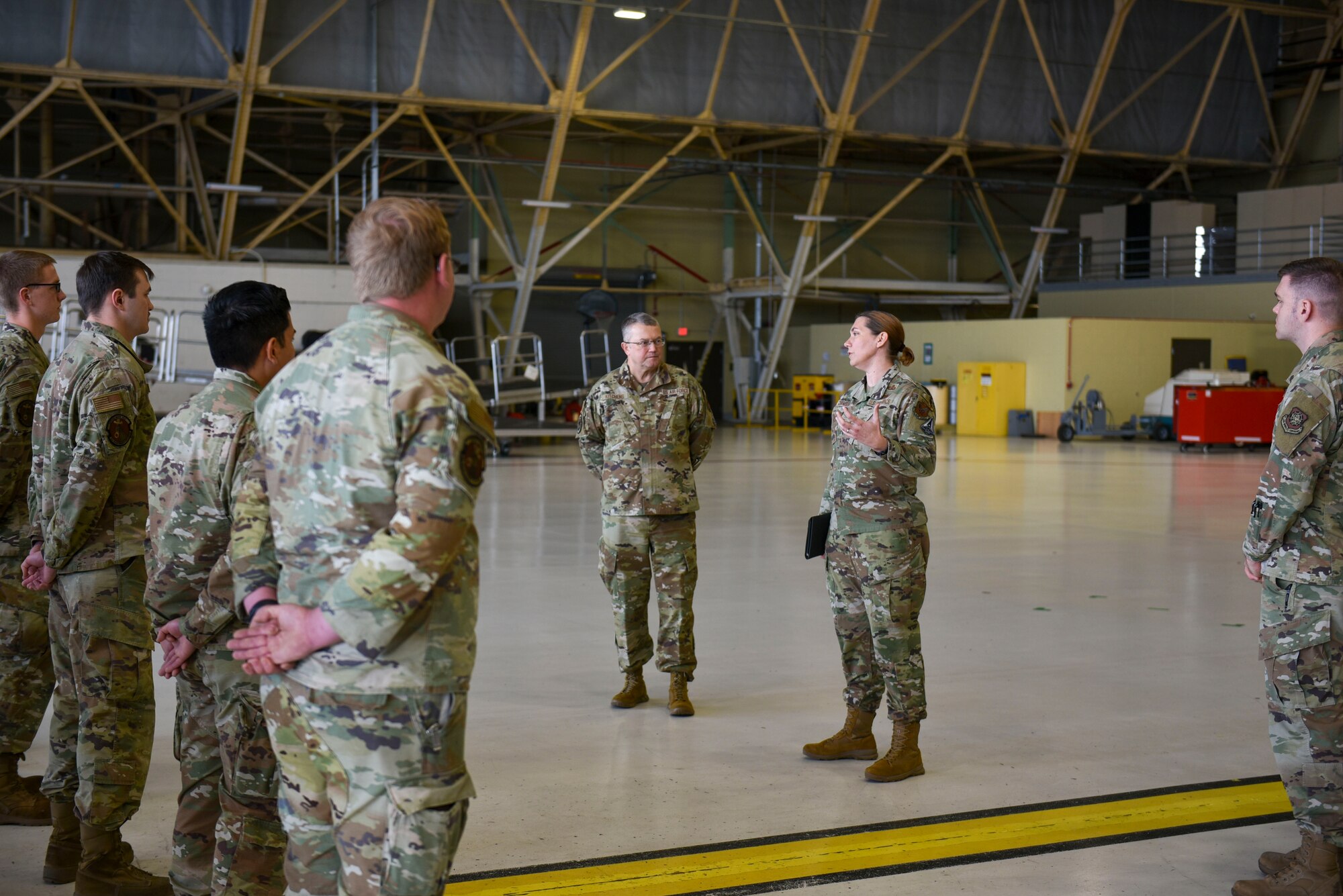 Maj. Gen. Randall Kitchens and Chief Master Sgt. Sadie Chambers stand in front of a formation of Airmen while addressing them.