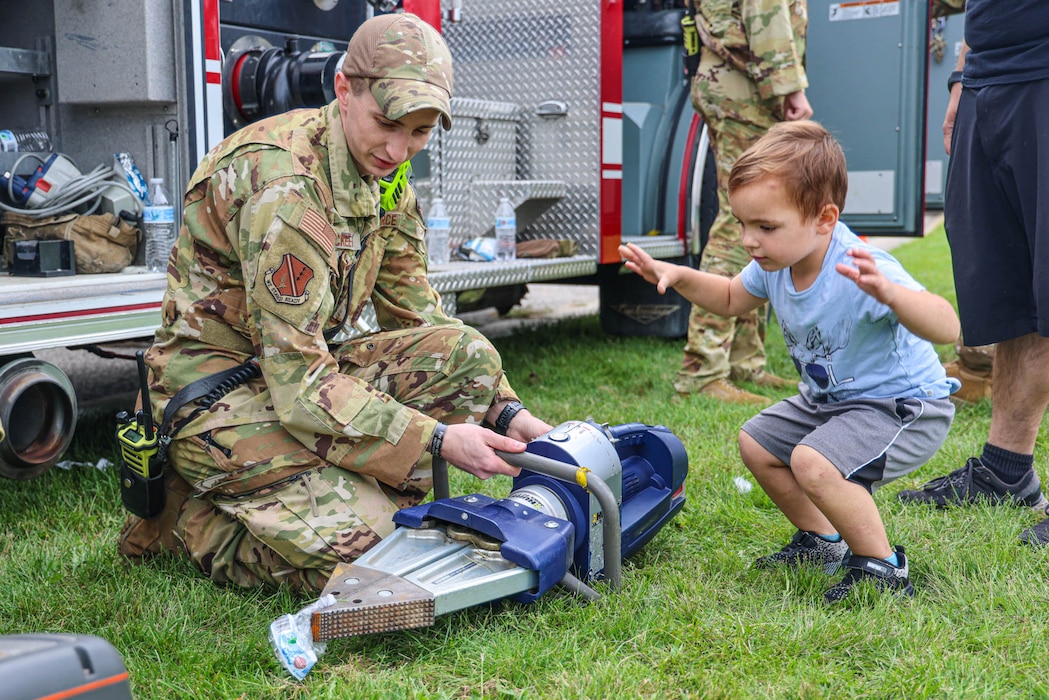 U.S. Air Force Staff Sgt. Paul Mckeever, a firefighter from the 127th Civil Engineer Squadron Fire Department, demonstrates firefighting tools to the child of a 127th Wing member during the unit's family appreciation day at Selfridge Air National Guard Base, Michigan.