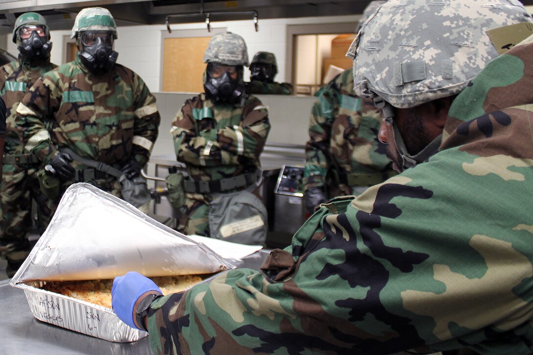 An Airman checks the temperature of food prior to lunch service, while wearing Mission Oriented Protective Posture (MOPP) gear during an exercise at Selfridge Air National Guard Base, Mich., Sept. 10, 2023.