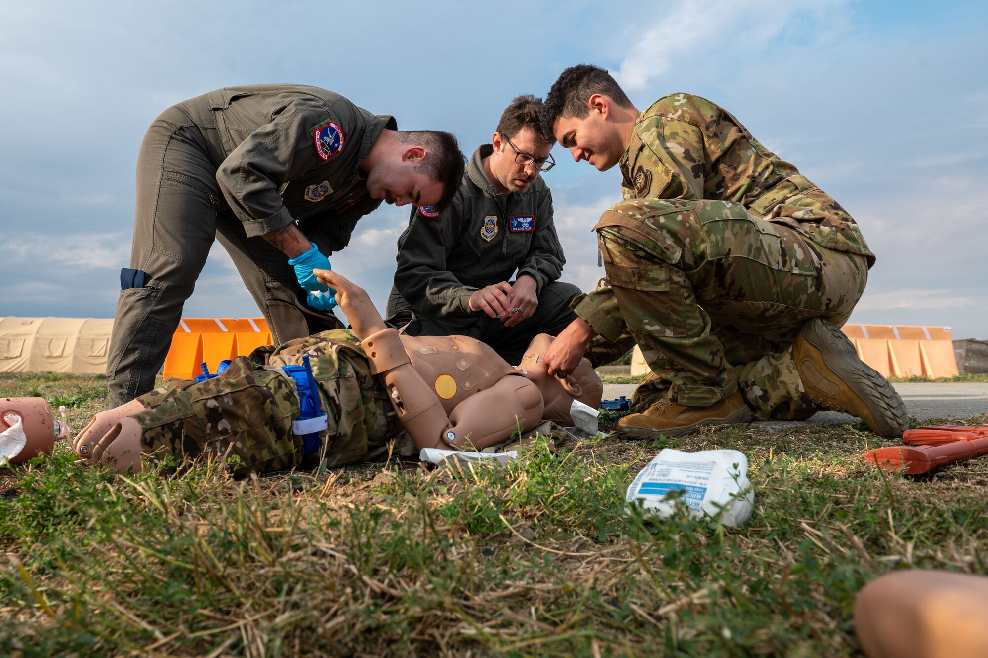 Senior Airman Jacob Ellis, left, Senior Airman Layrd Olliff, center, and Senior Airman Joshua Amos,  in-flight refueling specialists assigned to the 93rd Air Refueling Squadron, treat a simulated patient’s injuries during a “boom rodeo" hosted by the 92nd Operations Group at Fairchild Air Force Base, Washington, Sept. 20, 2023. During the rodeo, six air refueling squadrons competed in a forklift loading event, Tactical Combat Casualty Care and a water survival scenario. Scenarios like this enable Airmen to get hands-on training with tools to which they may not otherwise have access. These competitions also build camaraderie between units from different bases and provide friendly competition to motivate Airmen to perform their best. (U.S. Air Force photo by Airman 1st Class Morgan Dailey)