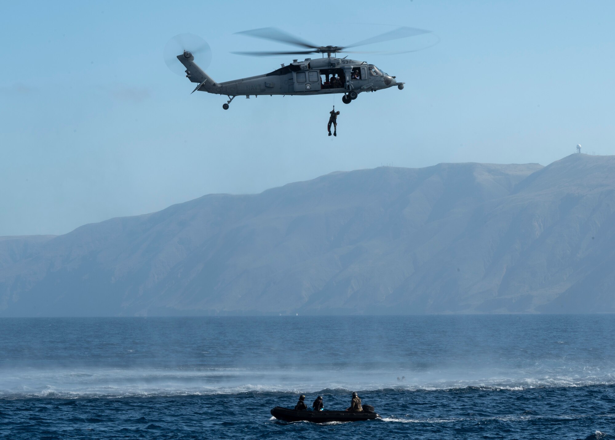 A U.S. Airman, training with the 68th Rescue Squadron, is hoisted from a Rigged Alternate Method Boat onto an MH-60 Seahawk aircraft off the coast of Calif., Sept. 13, 2023. The Airman used both the RAMB and the MH-60S to exfiltrate simulated casualties. (U.S. Air Force photo by Airman 1st Class William Finn V)
