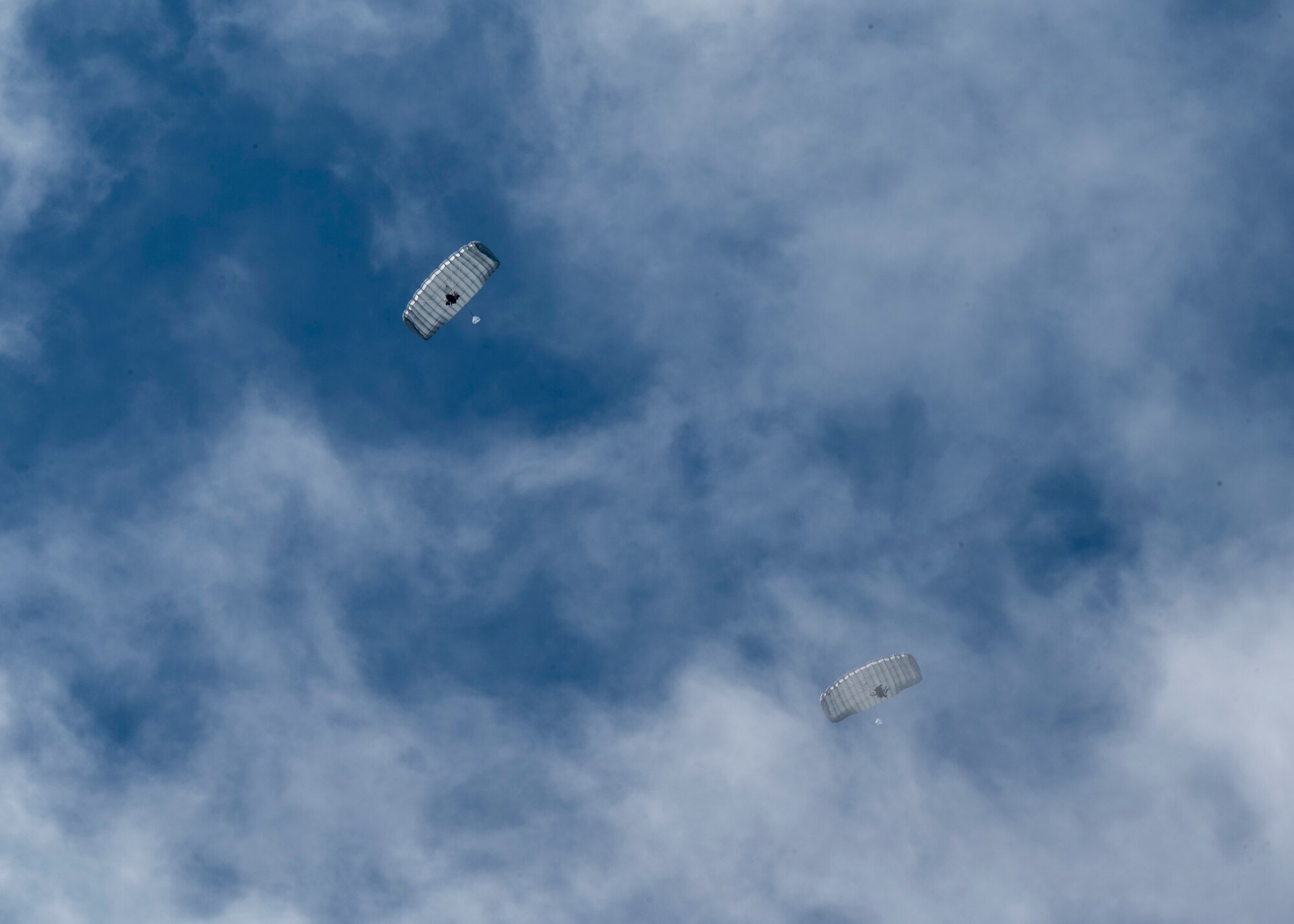 U.S. Airmen, training with the 68th Rescue Squadron, parachute through the air off the coast of Calif., Sept. 13, 2023. The Airmen parachuted down to the water, located a Rigged Alternate Method Boat and traveled to a site to rescue simulated casualties. (U.S. Air Force photo by Airman 1st Class William Finn V)