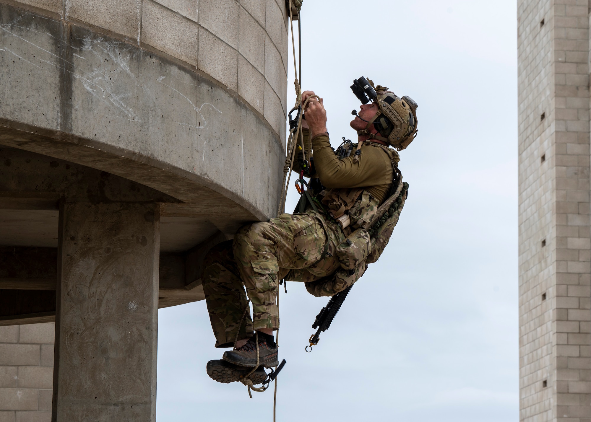 A U.S. Airman, training with the 68th Rescue Squadron, climbs up a balcony of a building at an UNDISCLOSED LOCATION, Calif., Sept. 17, 2023. The Airman searched for and rescued simulated casualties from the second floor of the building. (U.S. Air Force photo by Airman 1st Class William Finn V)