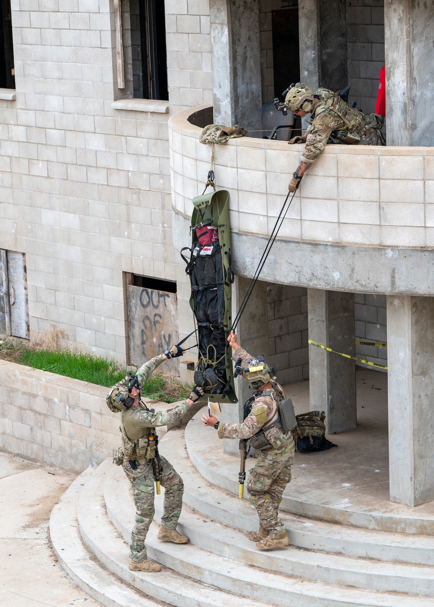 U.S. Airmen, training with the 68th Rescue Squadron, lower a simulated casualty from the second floor of a building at an UNDISCLOSED LOCATION, Calif., Sept. 17, 2023. The Airmen searched an entire mock village for over 30 casualties. (U.S. Air Force photo by Airman 1st Class William Finn V)