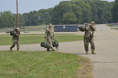Individuals carry deployment bags to tents
