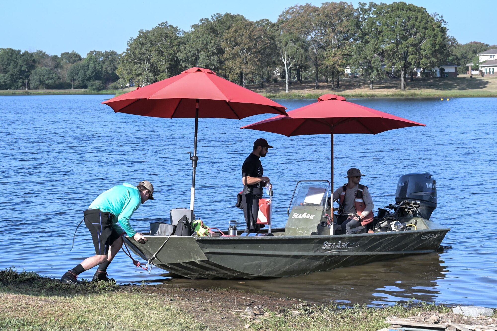 Man pushes boat into lake.