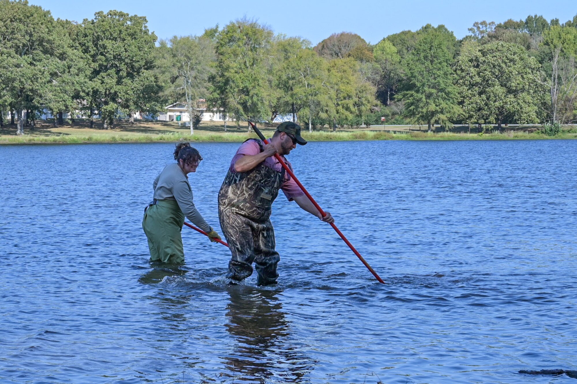 Man and woman rake rock structure in lake.