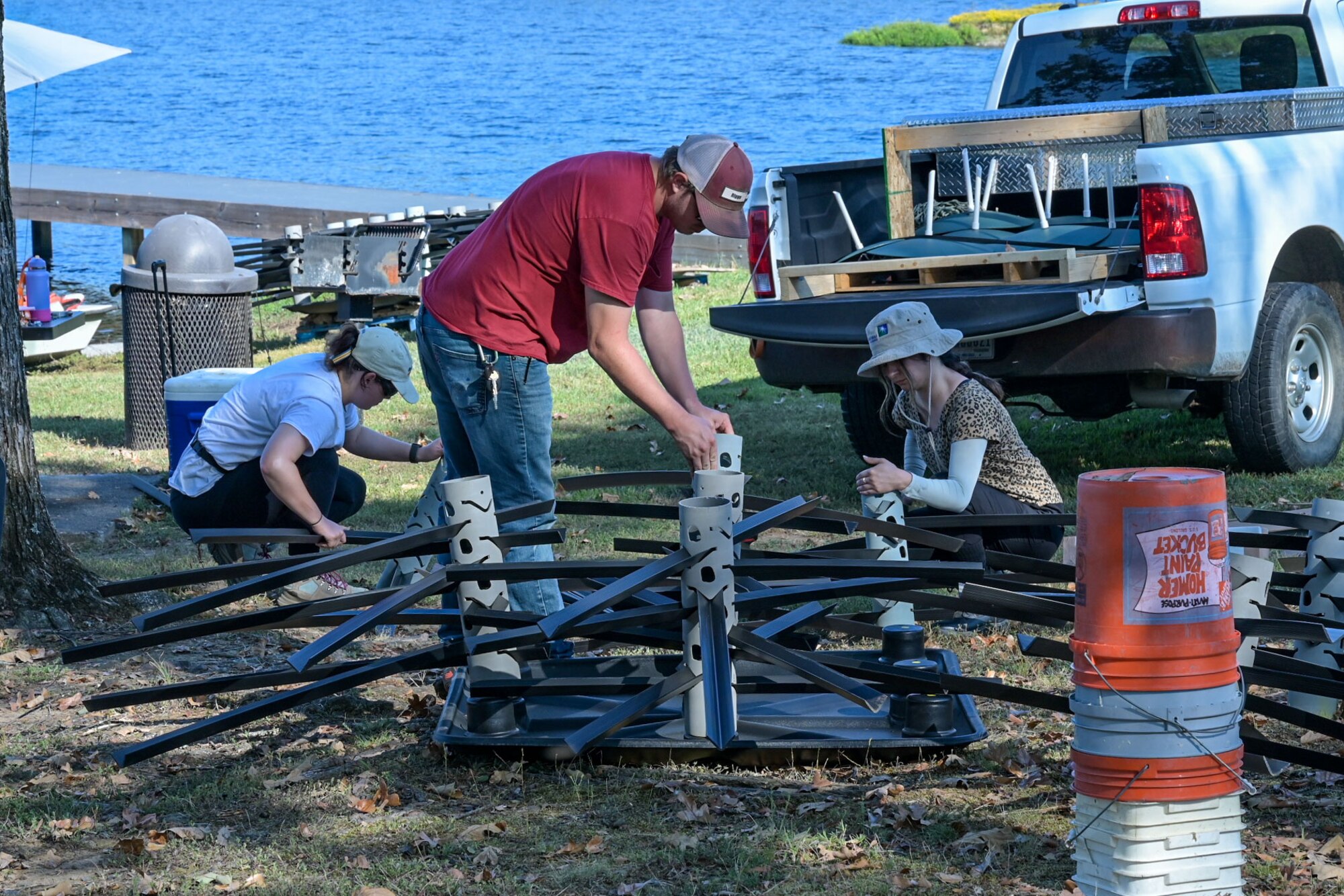 Two women and one man build a structure.