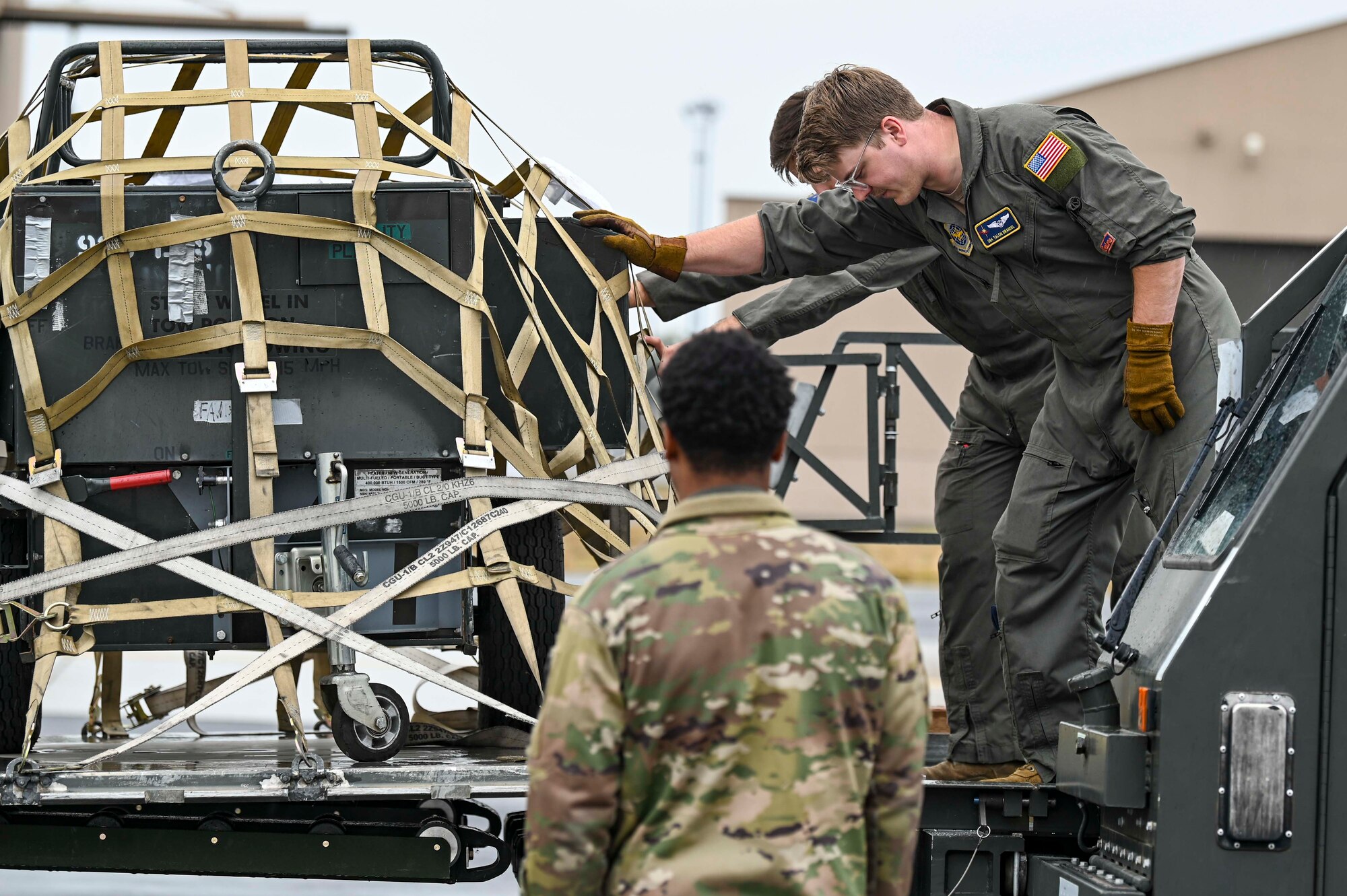 Airmen adjust a cargo net on top of cargo on a K-loader
