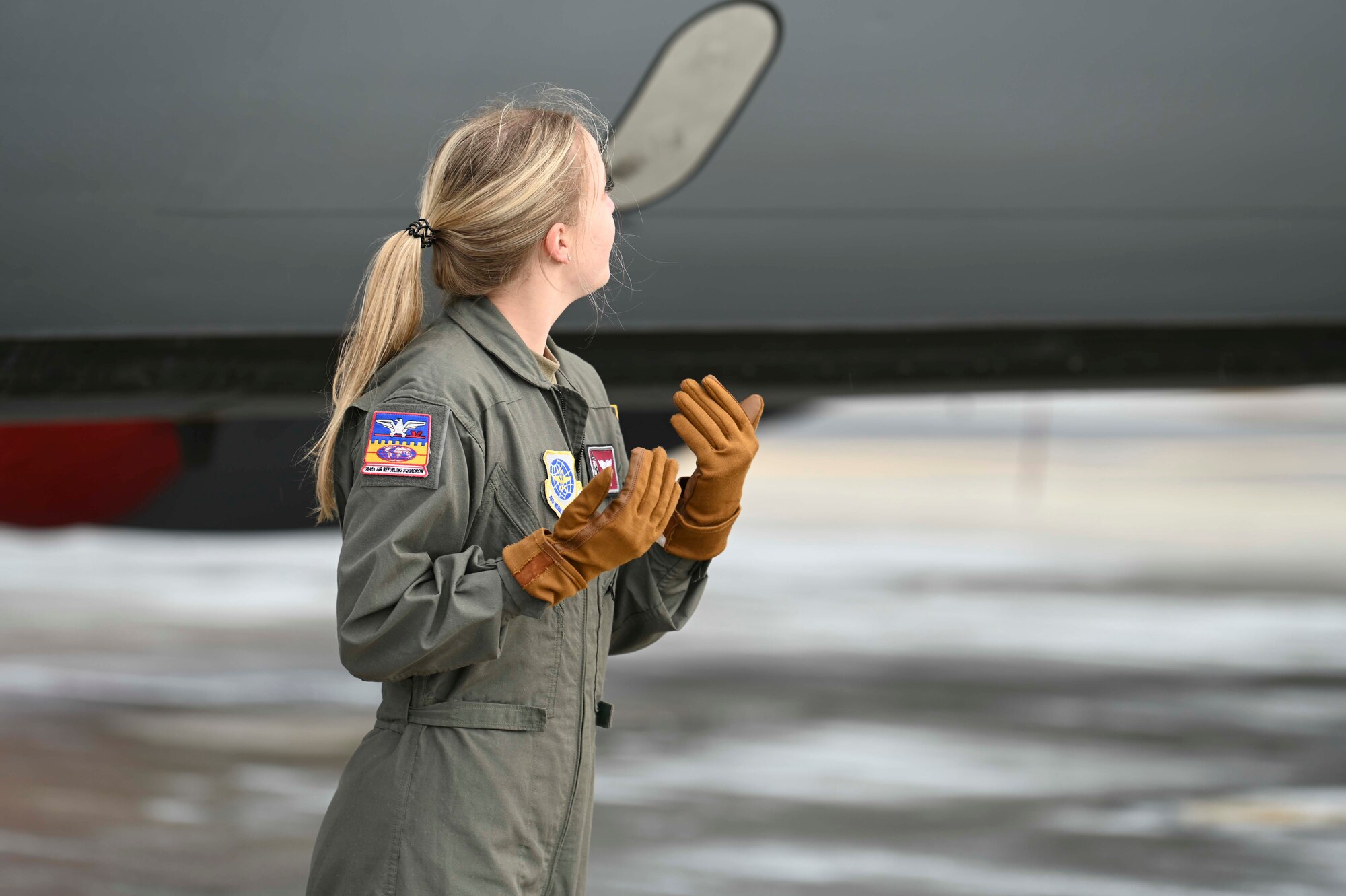 Airman 1st Class Sydnee Neal uses hand signals to instruct other Airmen who are maneuvering cargo into a KC-135 Stratotanker