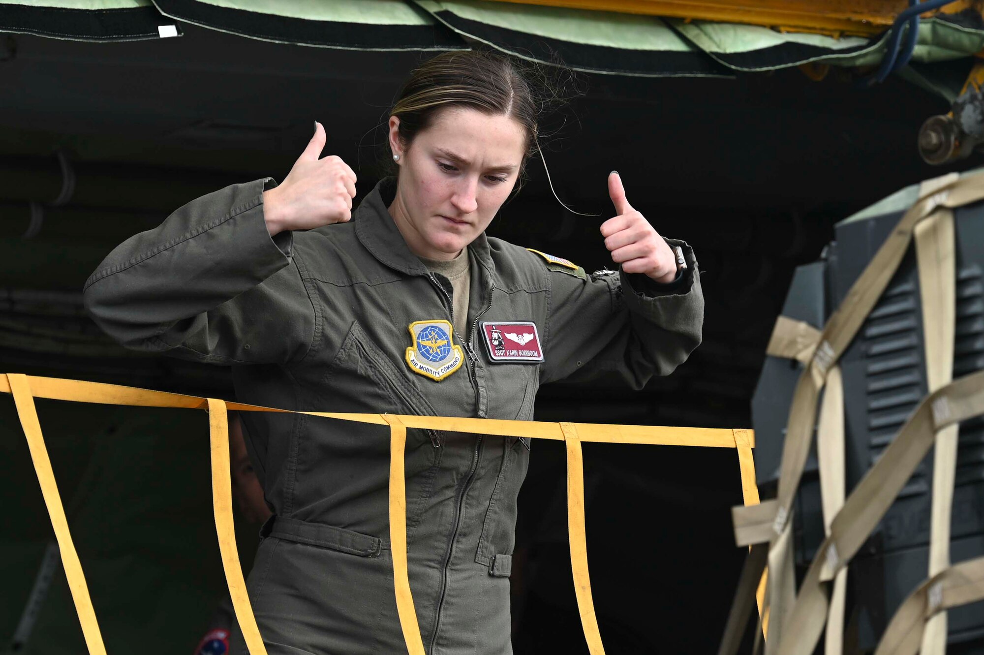 U.S. Air Force Staff Sgt. Karin Boerboom uses hand signal to instruct other Airmen on how to maneuver cargo into a KC-135 Stratotanker