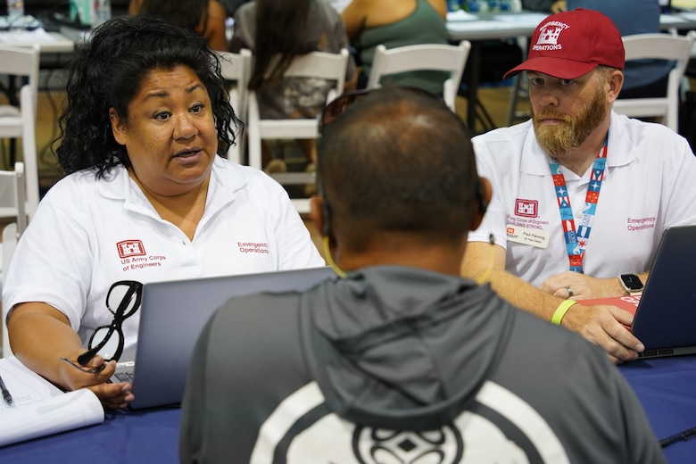 Two people talk with a man across the table from them.