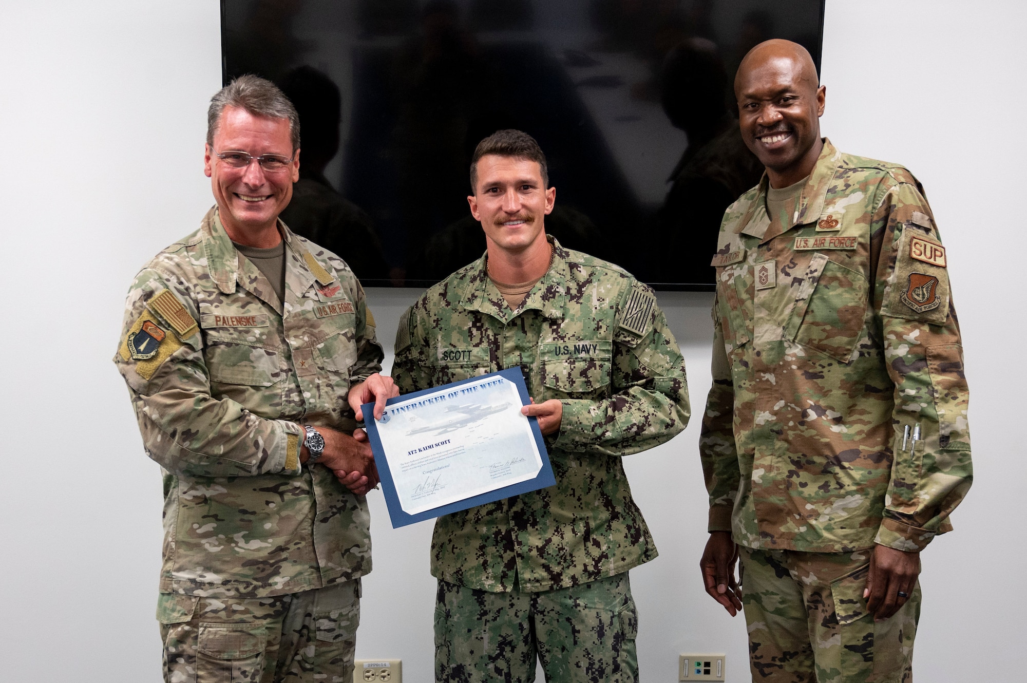 U.S. Navy Petty Officer 2nd Class Kaimi Scott, an aviation electronics technician assigned to the Unmanned Patrol Squadron (VUP) 19, receives the Linebacker of the Week Award from U.S. Air Force Brig. Gen. Thomas Palenske, commander of the 36th Wing, and U.S. Air Force Chief Master Sgt. Nicholas Taylor, the command chief of the 36th Wing, at Andersen Air Force Base, Guam, Sept. 27, 2023. The Team Andersen Linebacker of the Week recognizes outstanding enlisted, officer, civilian and total force personnel who have had an impact on achieving Team Andersen’s mission, vision and priorities. (U.S. Air Force photo by Airman 1st Class Emily Saxton)