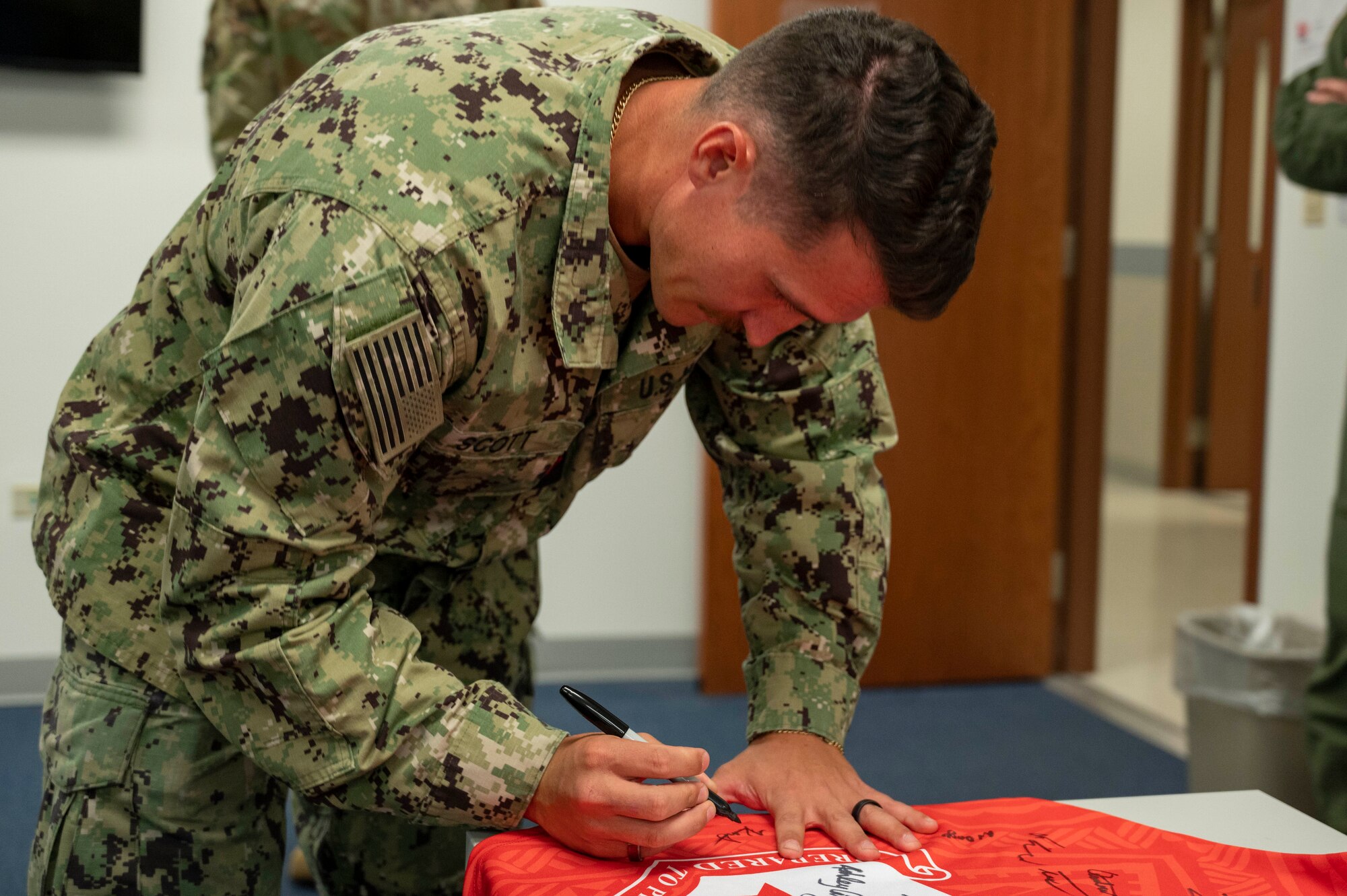 U.S. Navy Petty Officer 2nd Class Kaimi Scott, an aviation electronics technician assigned to the Unmanned Patrol Squadron (VUP) 19, signs the Linebacker of the Week jersey at Andersen Air Force Base, Guam, Sept. 27, 2023. The Team Andersen Linebacker of the Week recognizes outstanding enlisted, officer, civilian and total force personnel who have had an impact on achieving Team Andersen’s mission, vision and priorities. (U.S. Air Force photo by Airman 1st Class Emily Saxton)