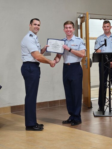 U.S. Air Force Major Nathan Demers presents A1C Owen Sanders with a certificate upon graduation from the Navy School of Explosive Ordnance Disposal in Eglin, Florida.