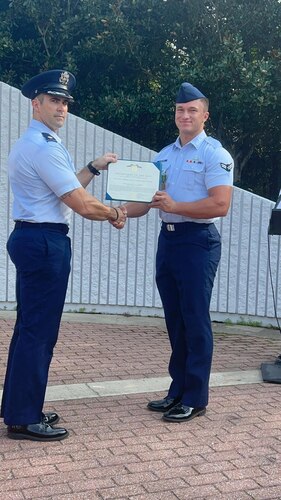 Air Force Major Nathan Demers presents Airman First Class Zane Schreiner with a certificate at his graduation from the Navy School of Explosive Ordnance Disposal in Eglin, Florida.