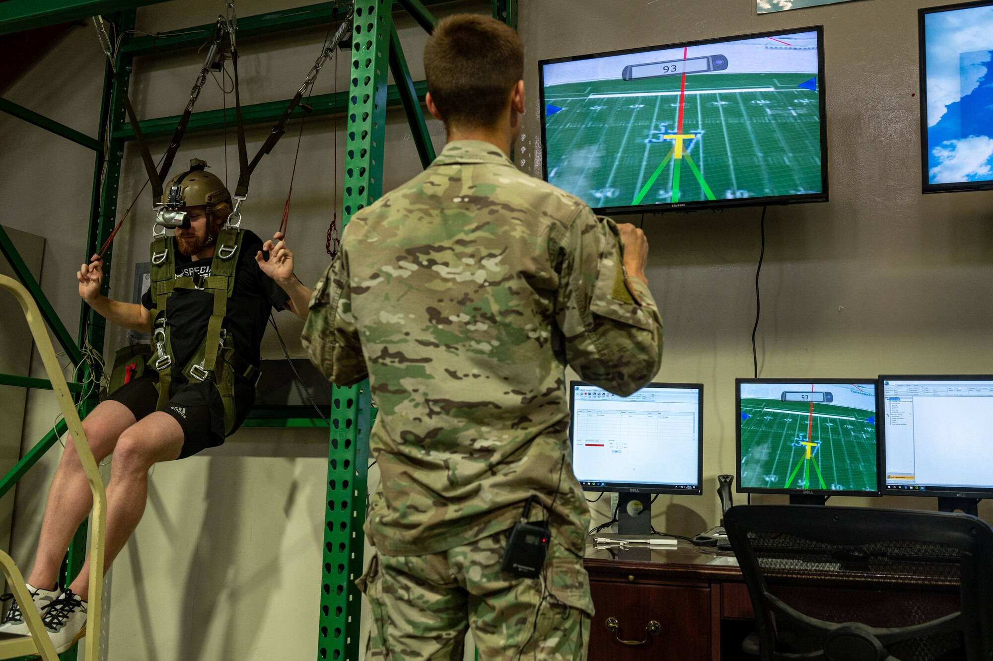A man suspends from a simulated parachute harness during a virtual reality parachute landing.