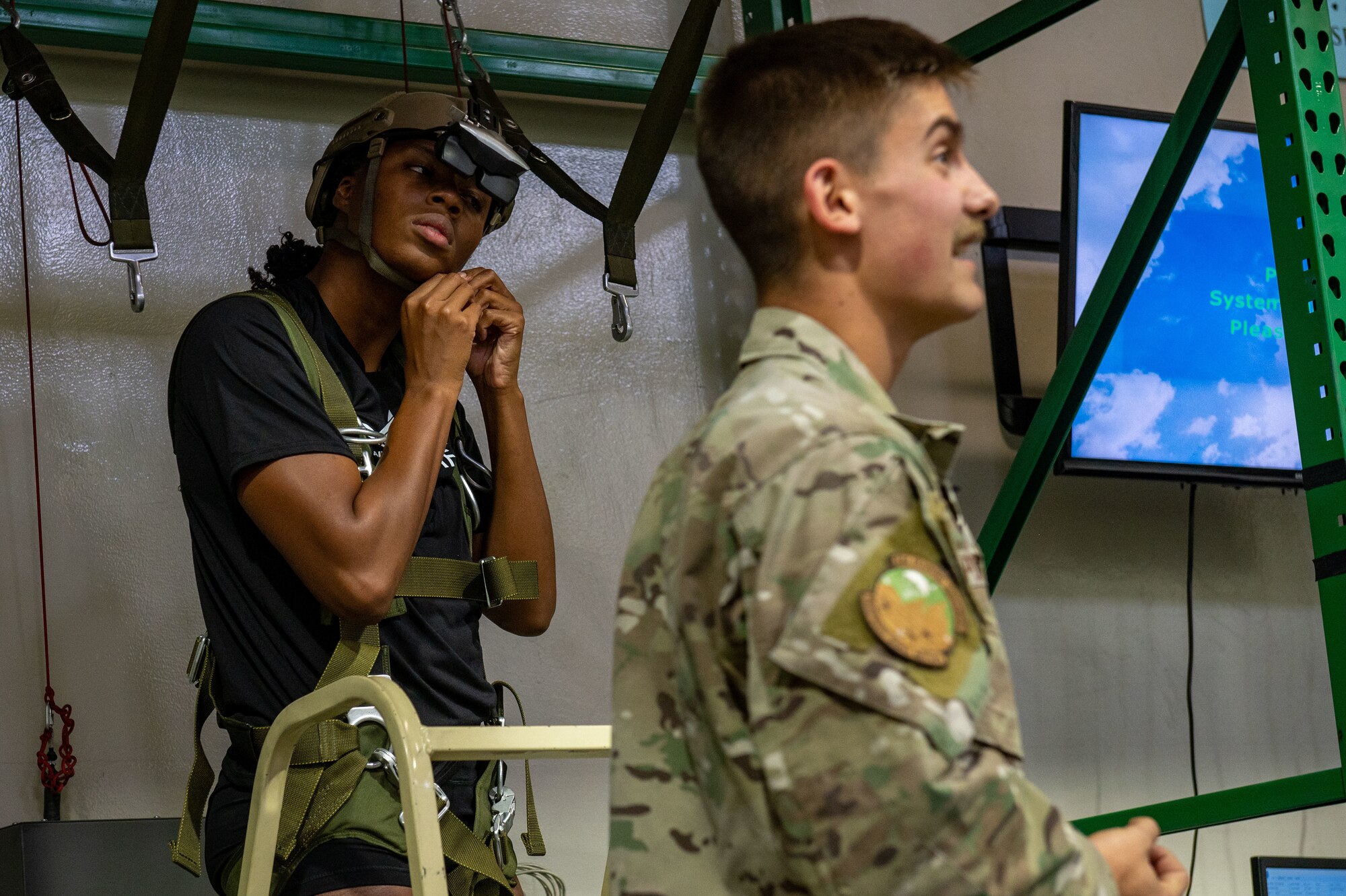 A woman straps into a harness and helmet before a virtual reality parachute landing.