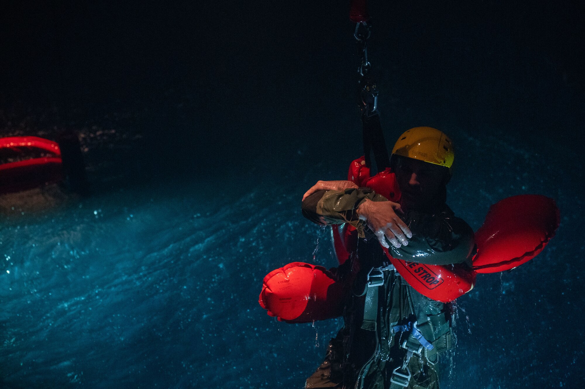 A U.S. Air Force student holds onto a harness during a simulated air lift rescue portion of a water survival course.