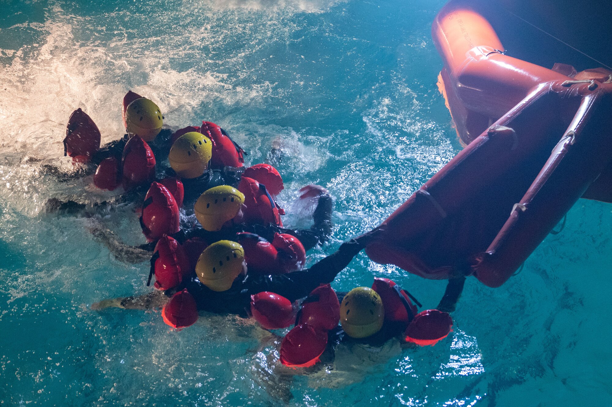 U.S. Air Force students swim to the entrance of a raft during a water survival course.